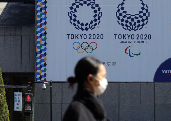 도쿄올림픽 홍보물이 설치된 일본 도쿄 거리를 마스크를 쓴 여성이 지나가고 있다. /연합뉴스