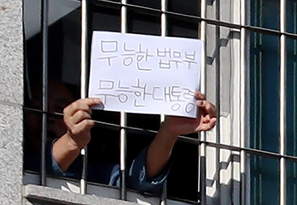 서울 송파구 동부구치소에서 6일 오후 한 수용자가 '무능한 법무부 무능한 대통령'이라고 쓴 종이를 창문 밖으로 취재진에게 내보이고 있다. /연합뉴스