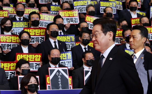 이재명 대통령이 4일 내년도 정부 예산안에 대한 시정연설을 하기 위해 서울 여의도 국회에 도착해 침묵시위를 하는 국민의힘 의원들 앞을 지나고 있다. 국민의힘 의원들은 추경호 전 원내대표에 대한 내란특검팀의 영장청구를 규탄하는 피켓을 들고서 침묵시위를 했다. /연합뉴스